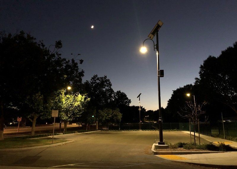 A street light is lit up in a parking lot at night