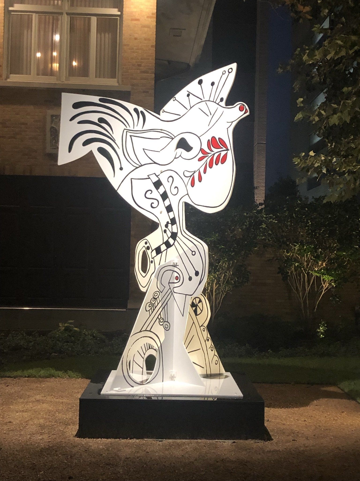 A statue of a bird is sitting in front of a house