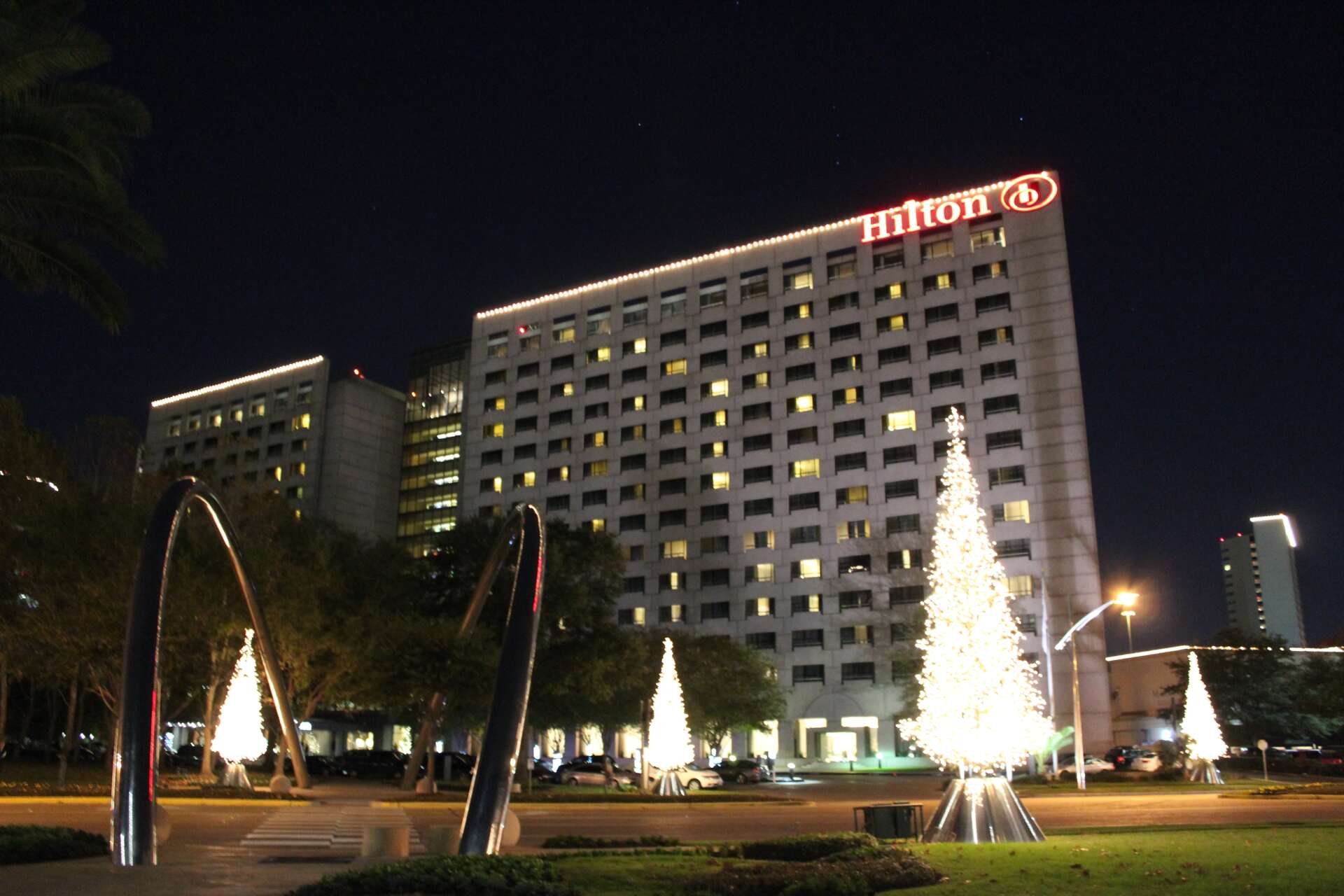 A hilton hotel at night with christmas trees in front of it