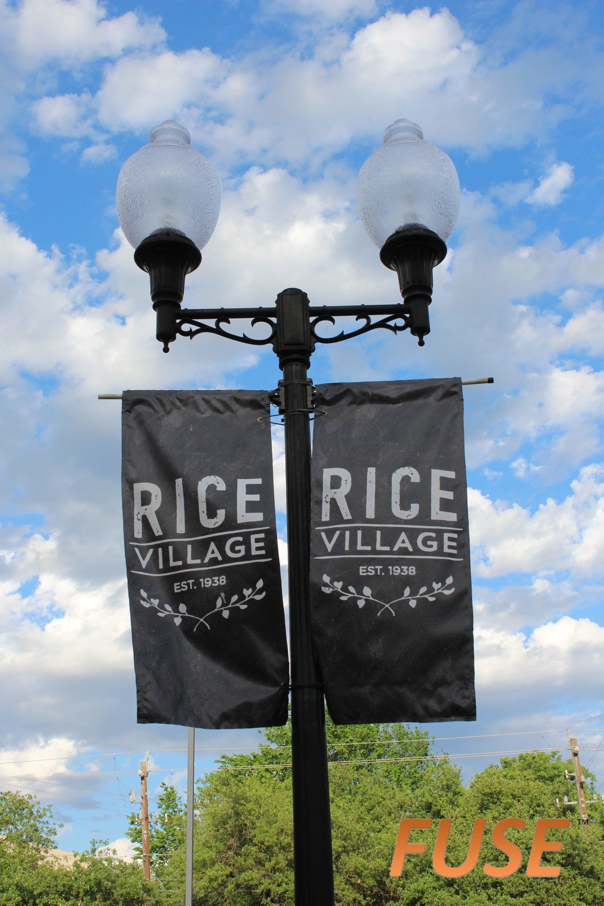 A street light with two banners that say rice village