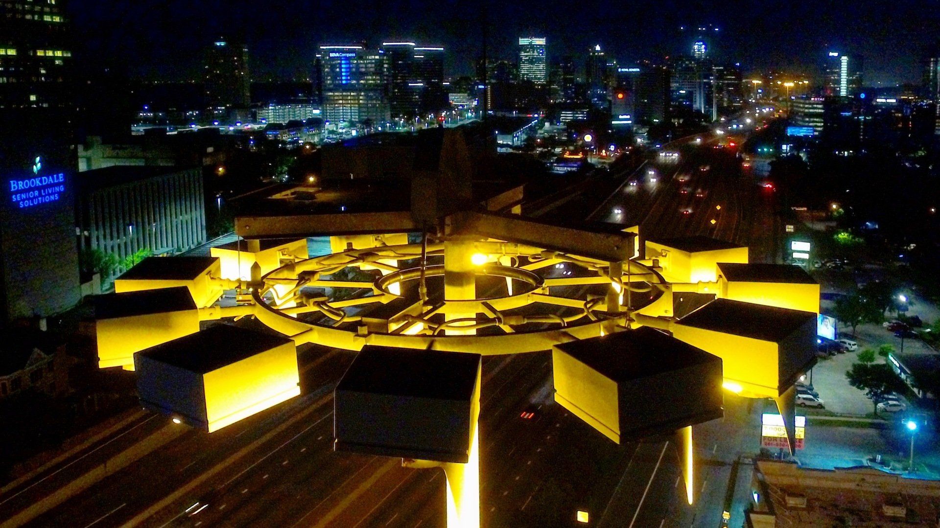 An aerial view of a city at night with a ferris wheel in the foreground