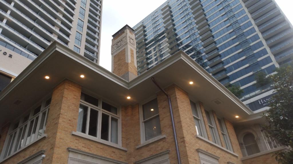 A large brick building with a clock tower in front of a tall building.