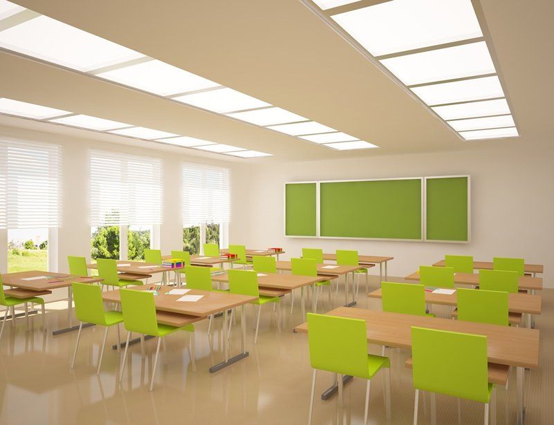 An empty classroom with green chairs and tables