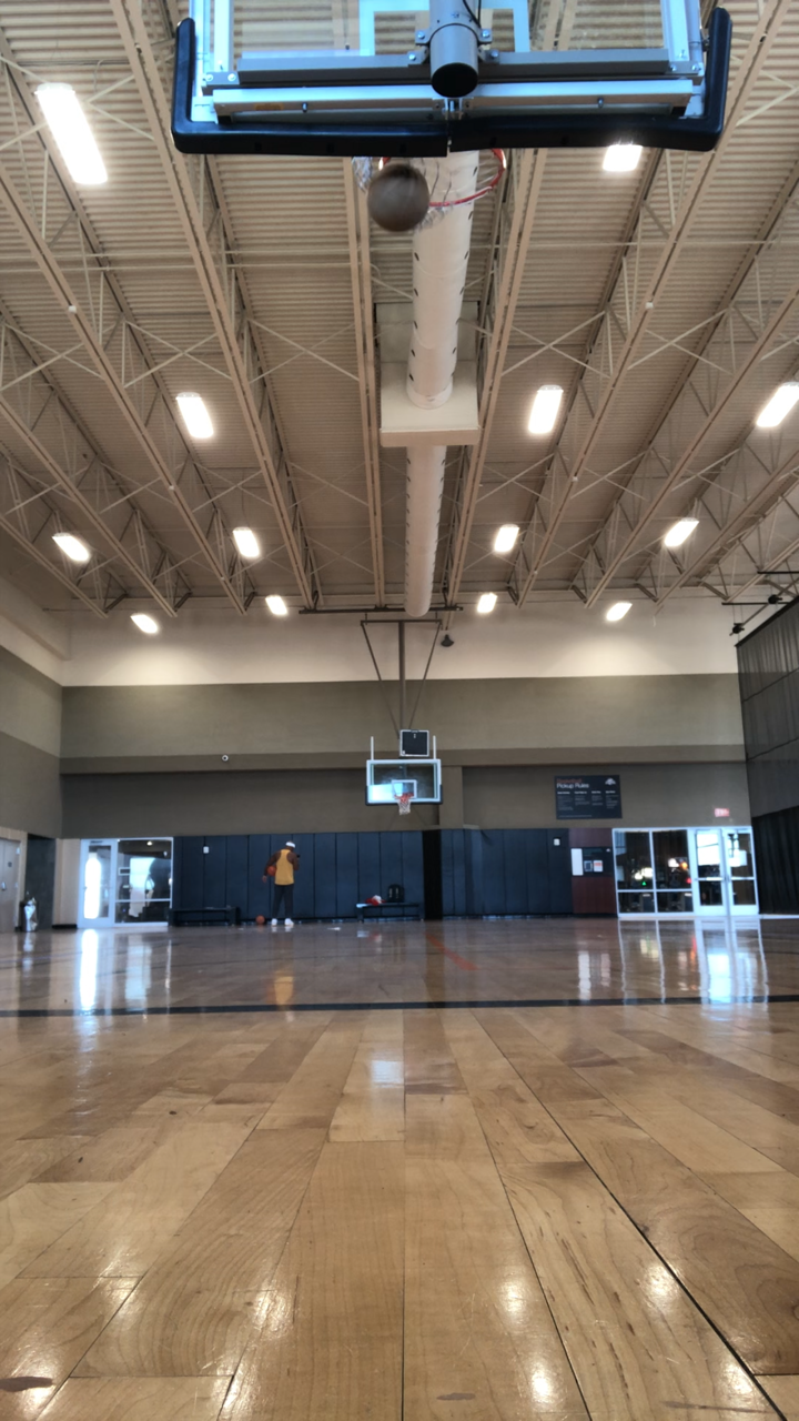 A basketball hoop is hanging from the ceiling of a gym.