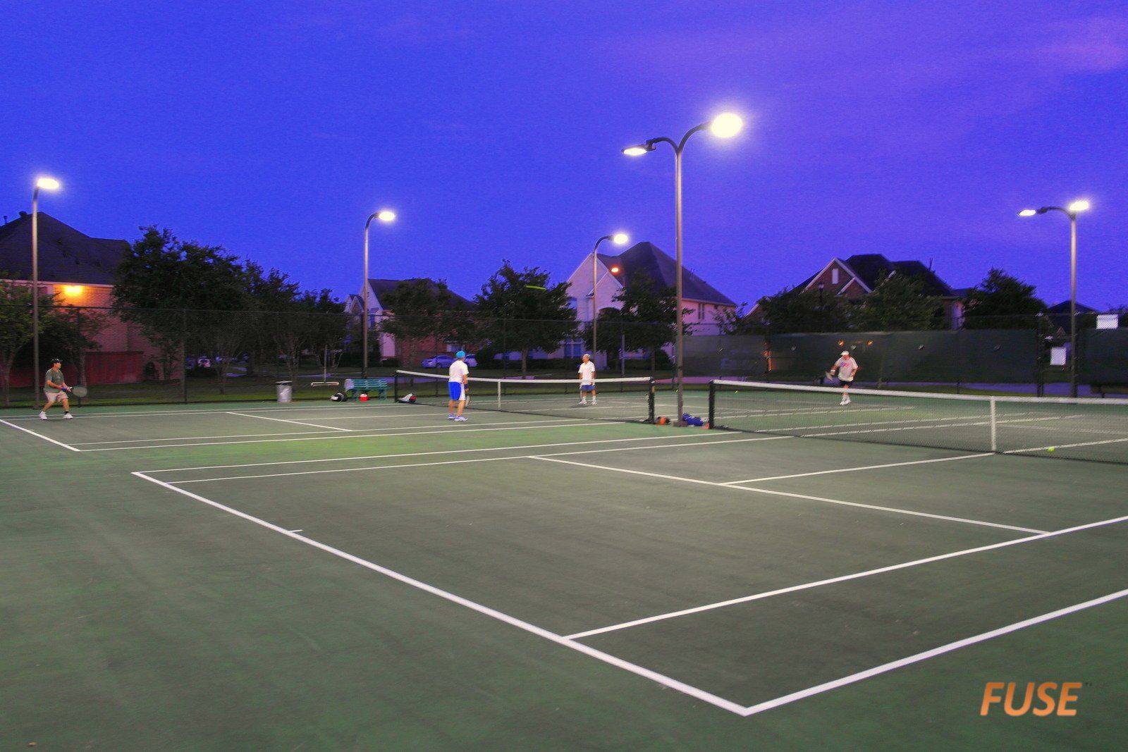 Two people are playing tennis on a tennis court at night