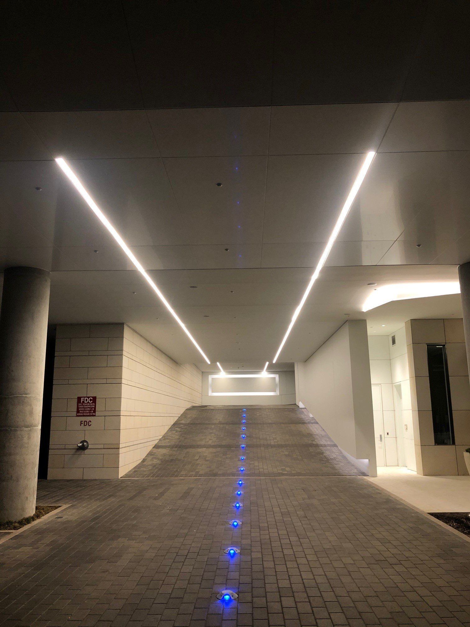 A parking garage is lit up at night with blue lights on the ground