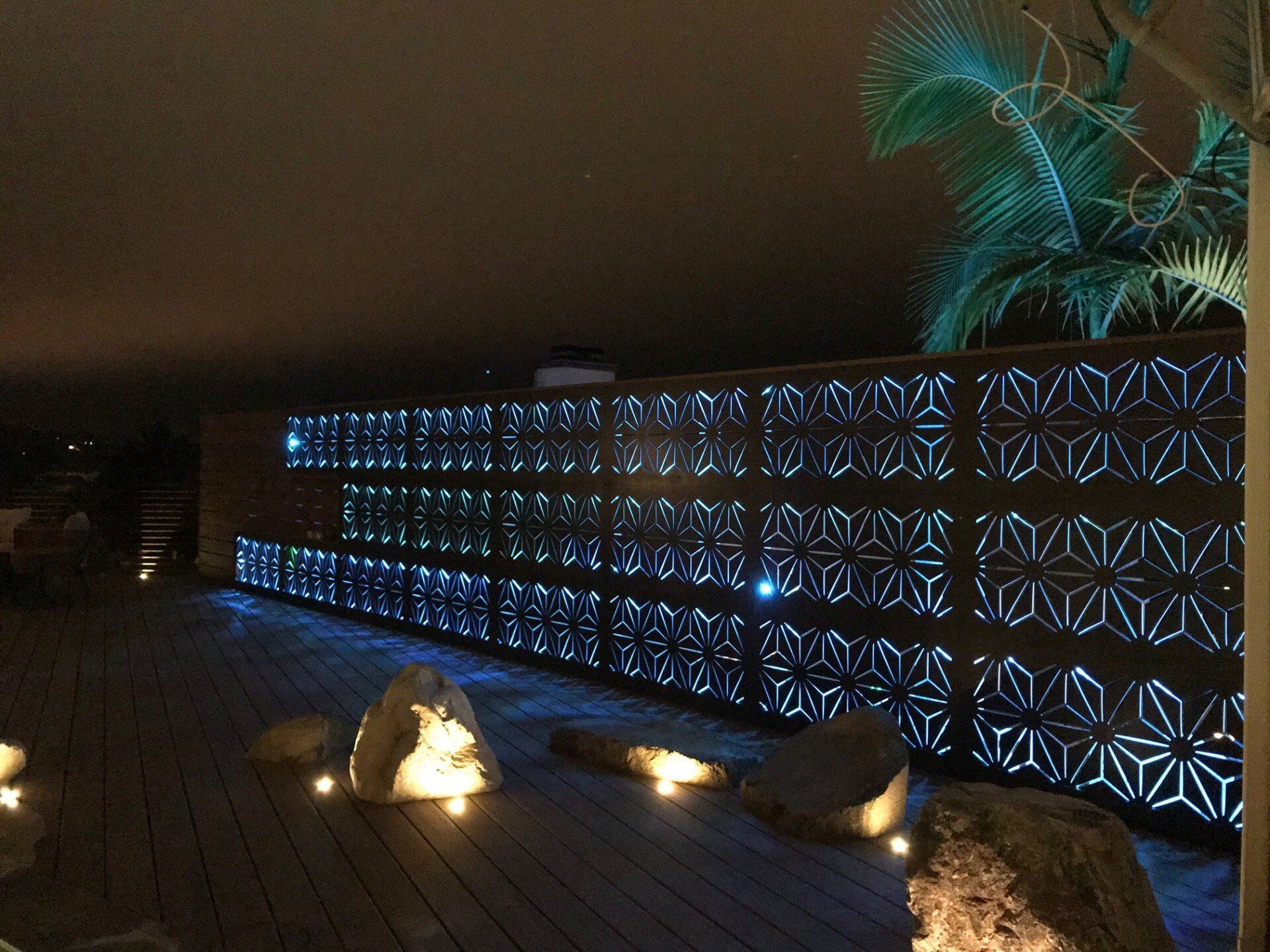 A wooden deck with a fence in the background at night
