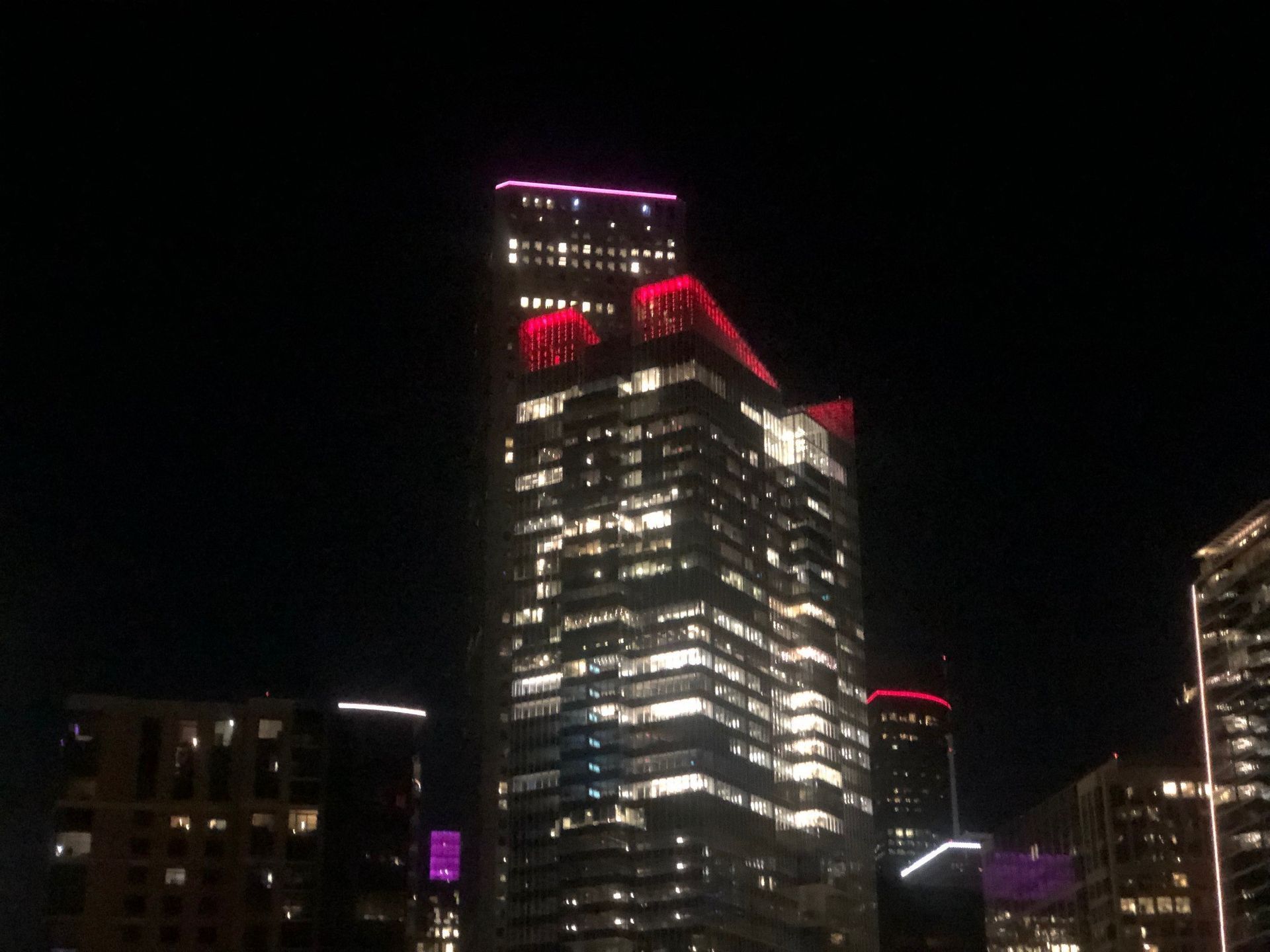 A city skyline at night with a few buildings lit up