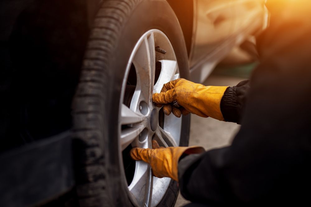 A Person Is Changing a Tire on A Car — Rasmussen Mechanical & Tyres in Garbutt, QLD