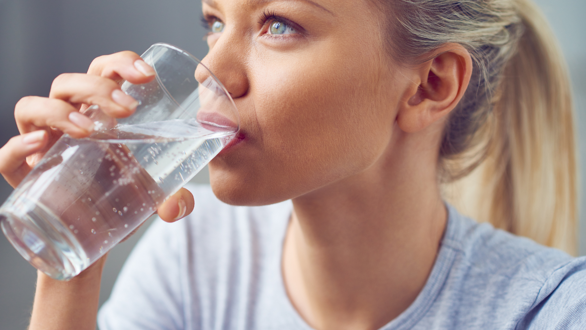 A woman is drinking a glass of water.