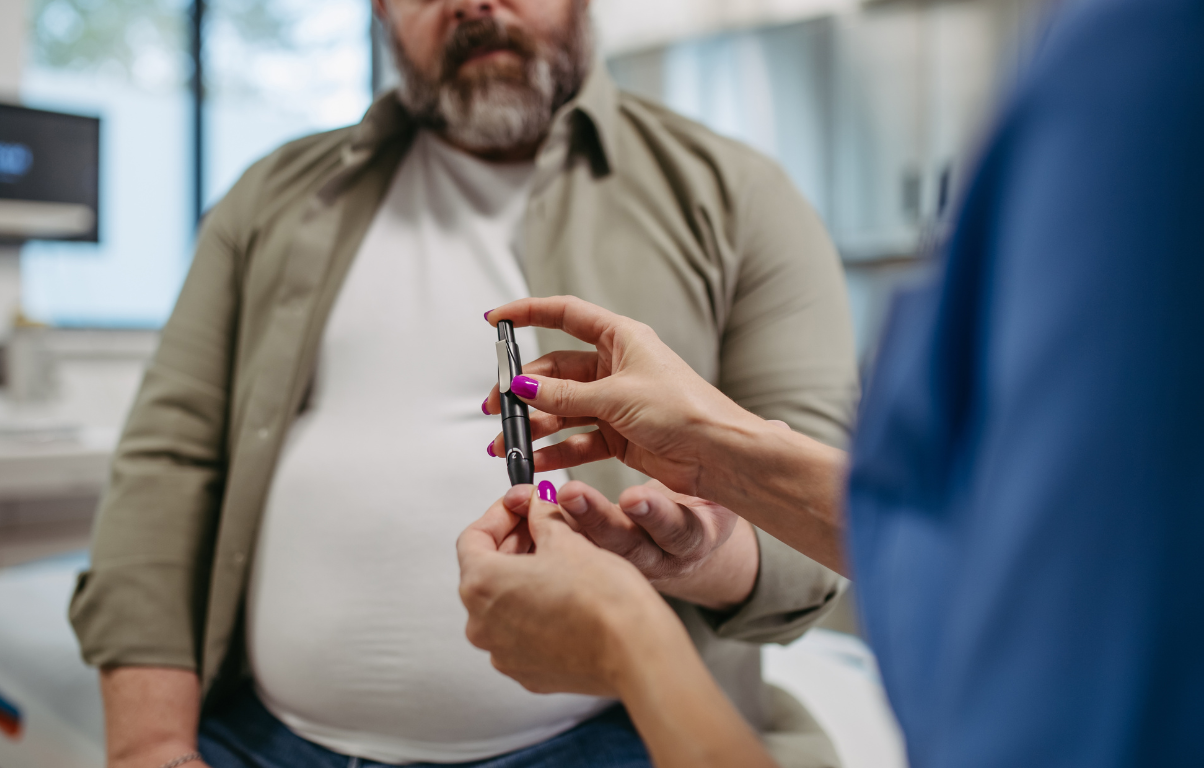 A healthcare provider demonstrating the use of a diabetes testing device to a middle-aged man, highlighting diabetes management in a clinical setting.