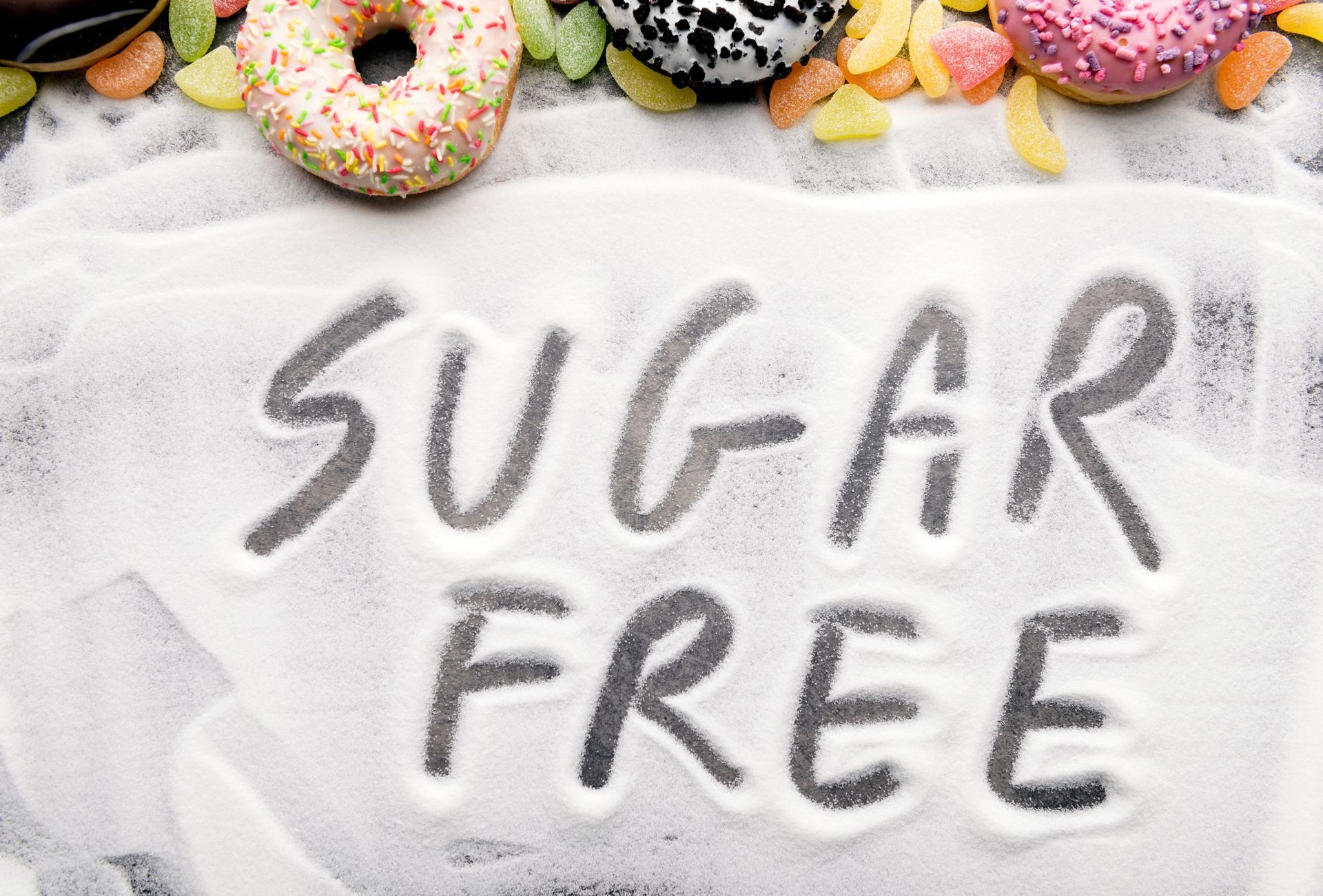 The word sugar free is written in powdered sugar surrounded by donuts and candy.