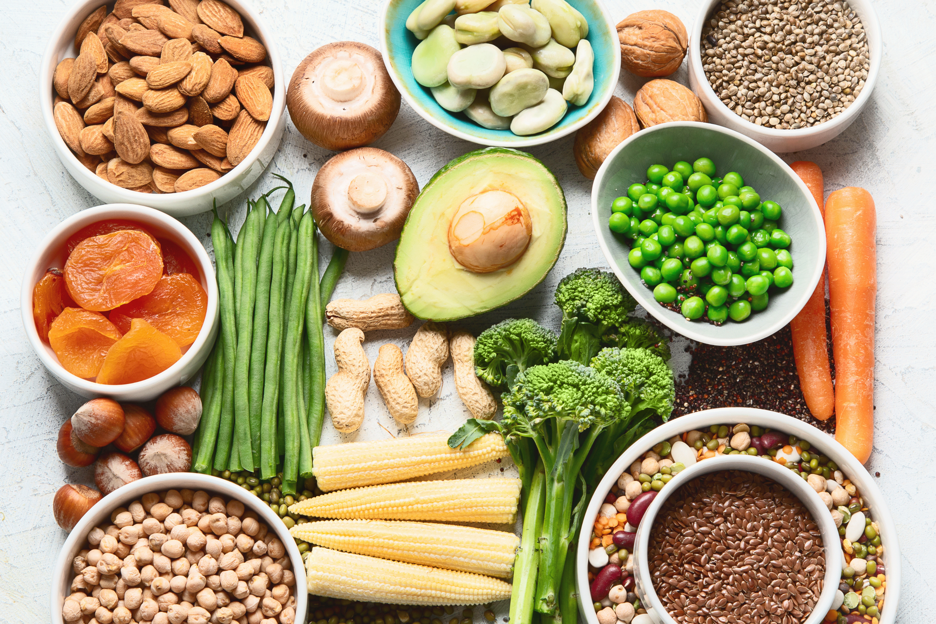 A variety of vegetables and nuts in bowls on a table.