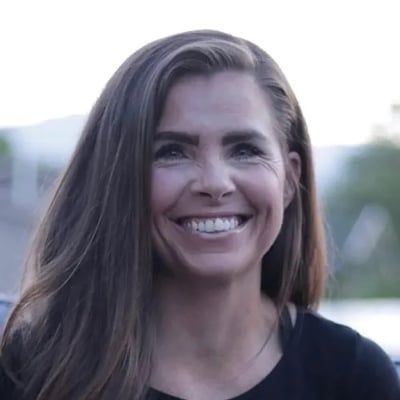 A woman with long hair is smiling and wearing a black shirt.