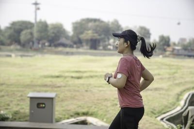 A woman in a red shirt and black pants is running in a field.