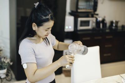 A woman is pouring water from a bottle into a glass.