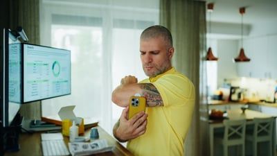 A man with a tattoo on his arm is holding a cell phone.