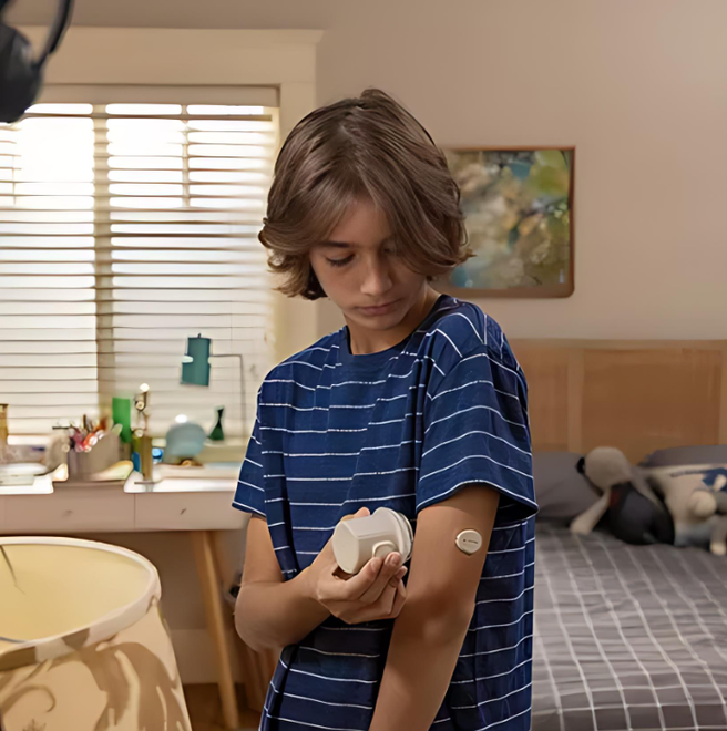 A young boy in a blue striped shirt has a patch on his arm