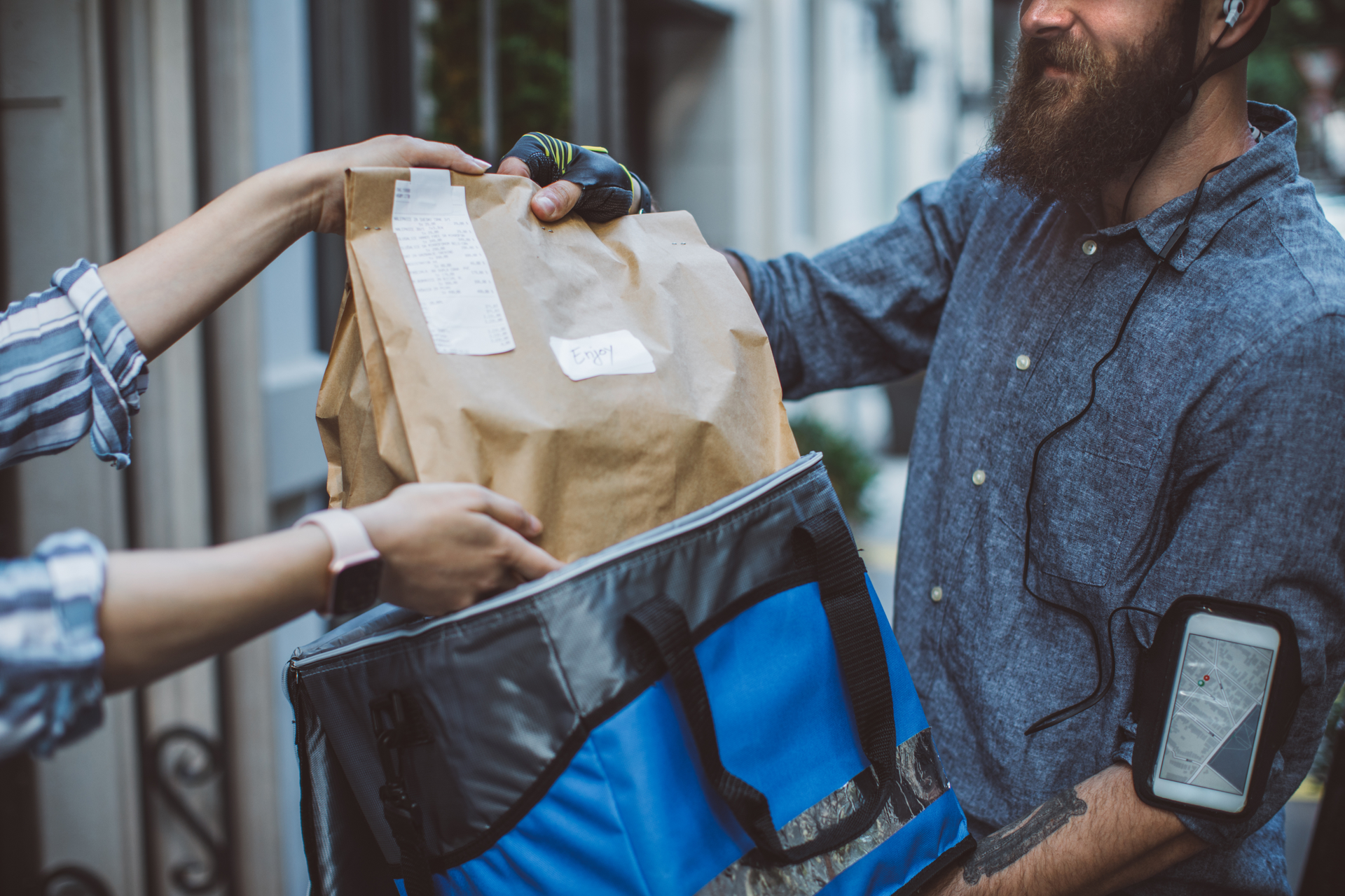 A man is delivering a bag of food to a woman.