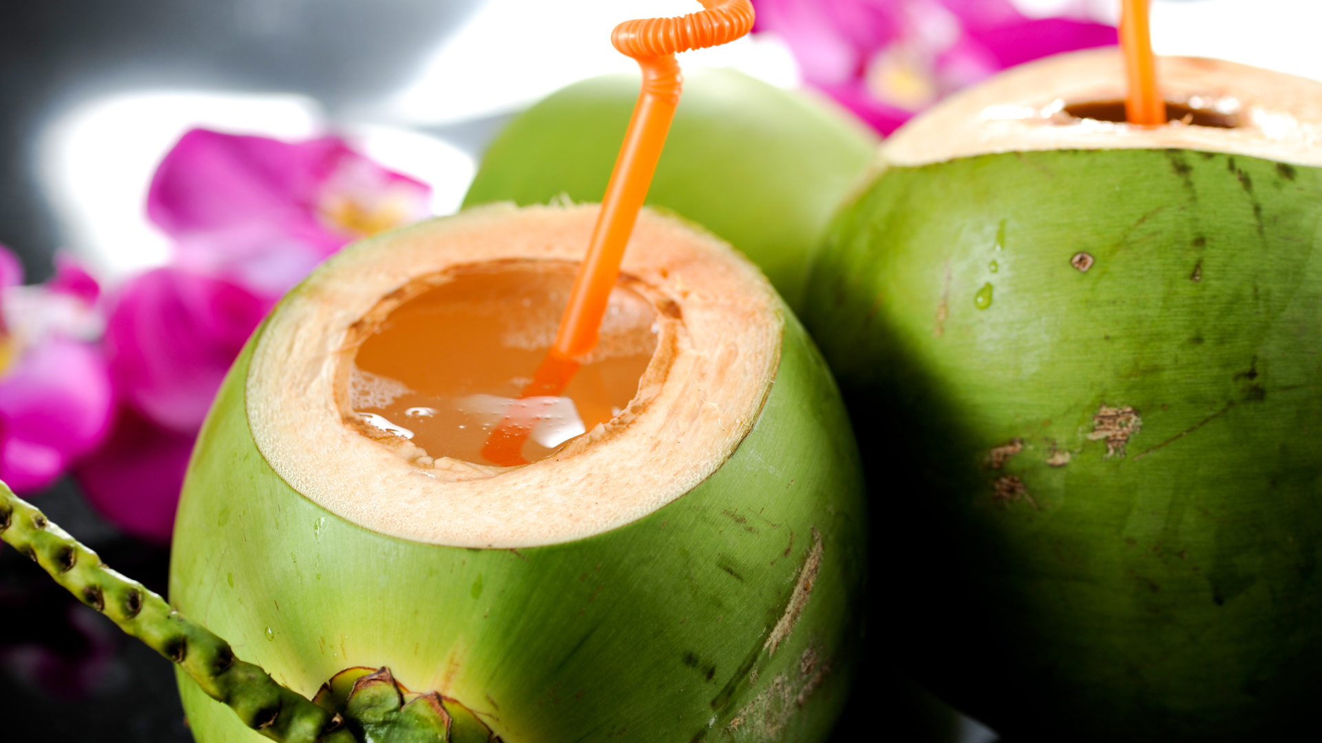 A close up of a coconut with a straw in it.