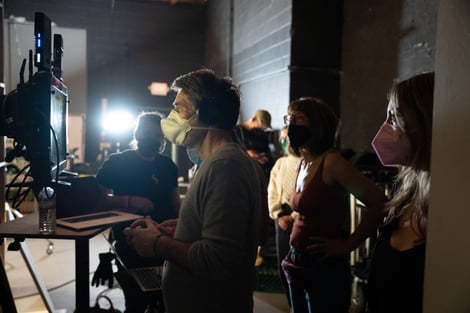 A group of people wearing masks are standing in a dark room.