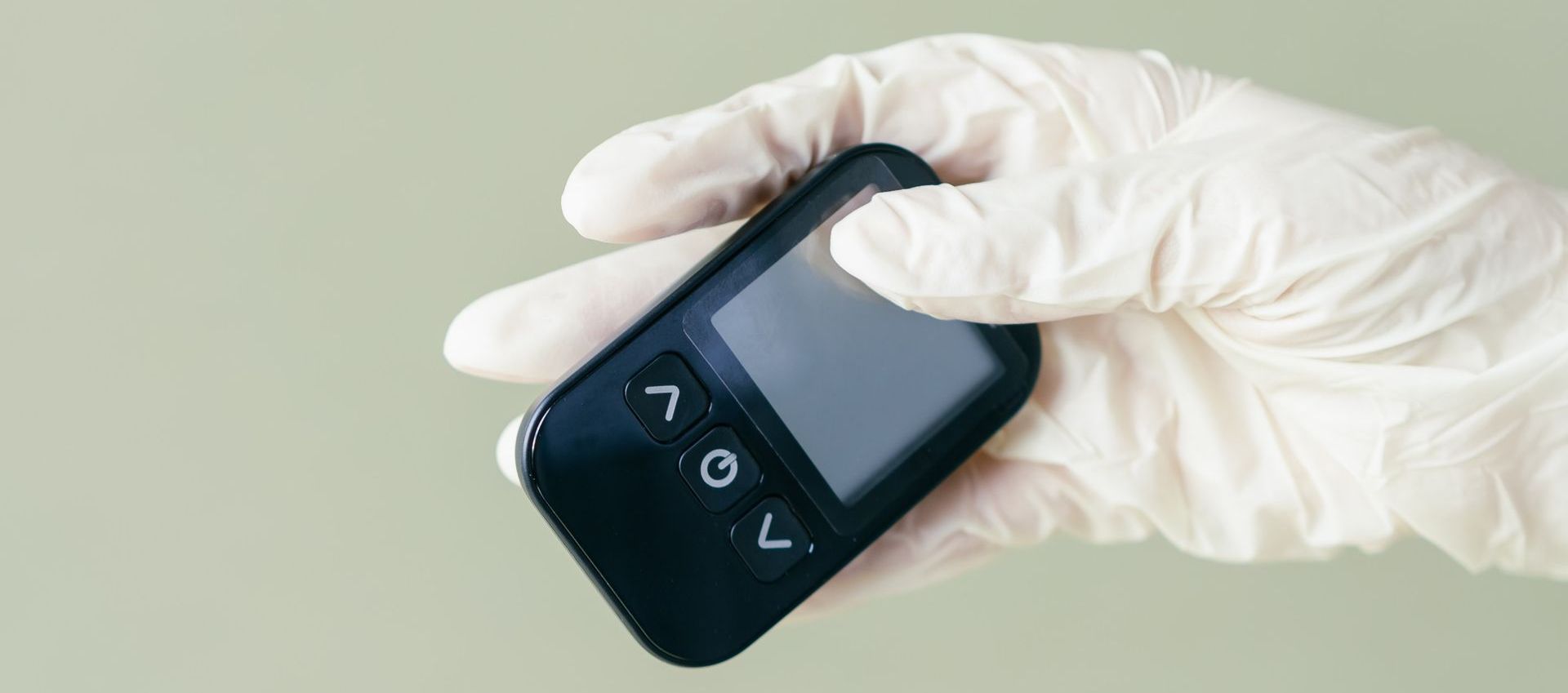 gloved hand holding a diabetic monitor