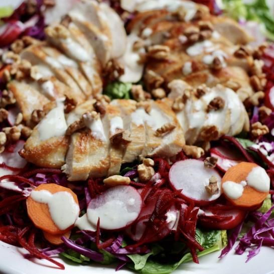 A close up of a salad with chicken and vegetables