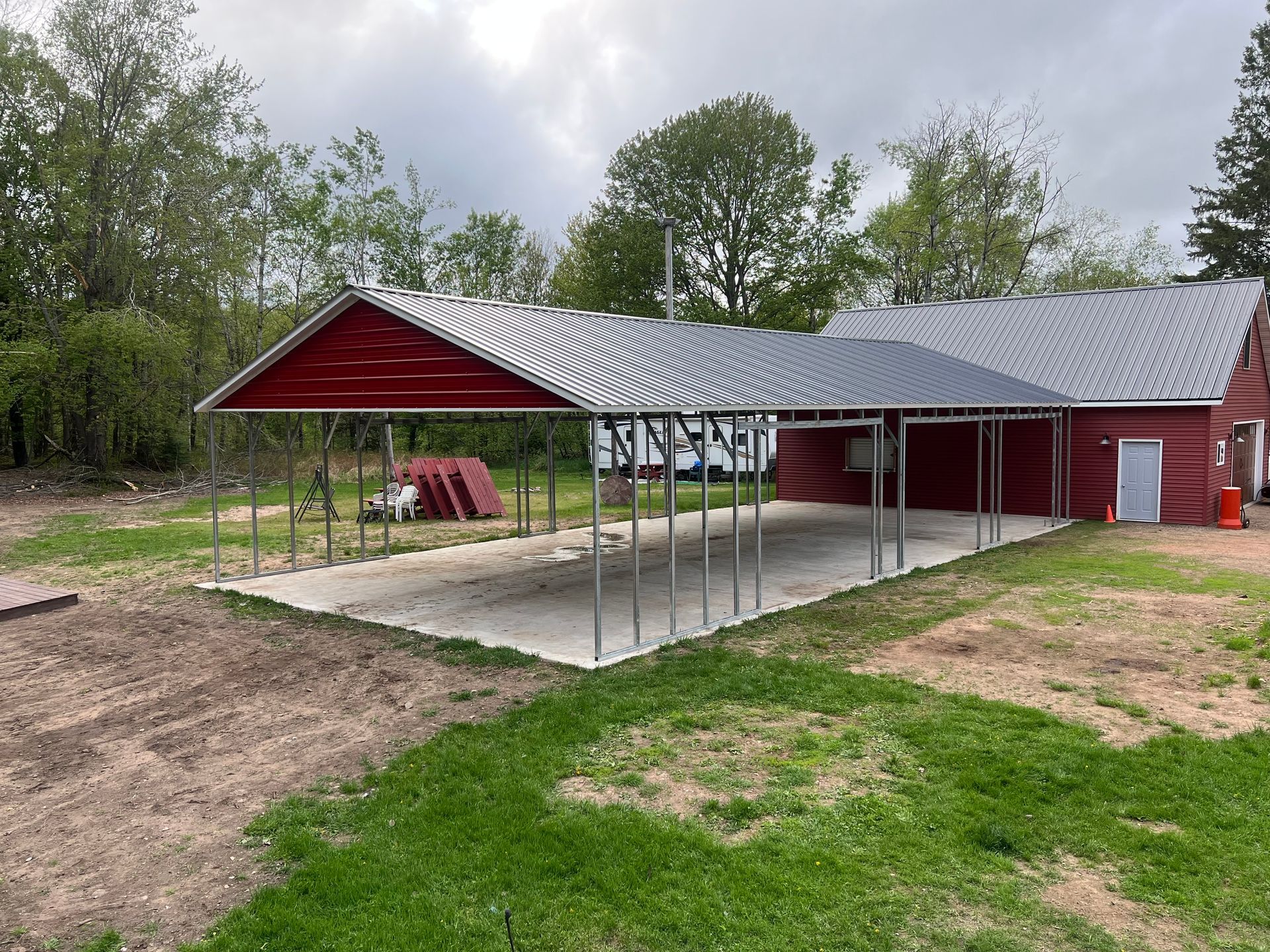 A man is walking in front of a metal carport.