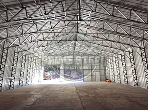 A large shed is sitting in the middle of a dirt field.