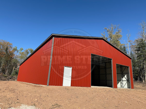 A red barn with a white roof is sitting in the middle of a grassy field.