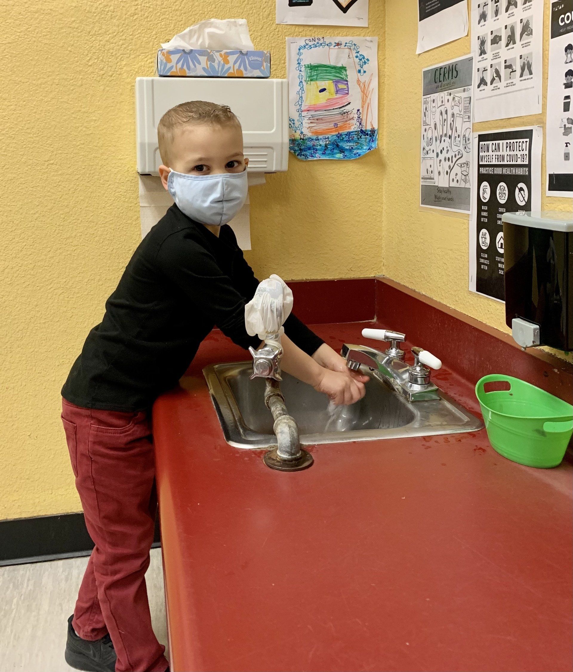 Child with mask washing hands