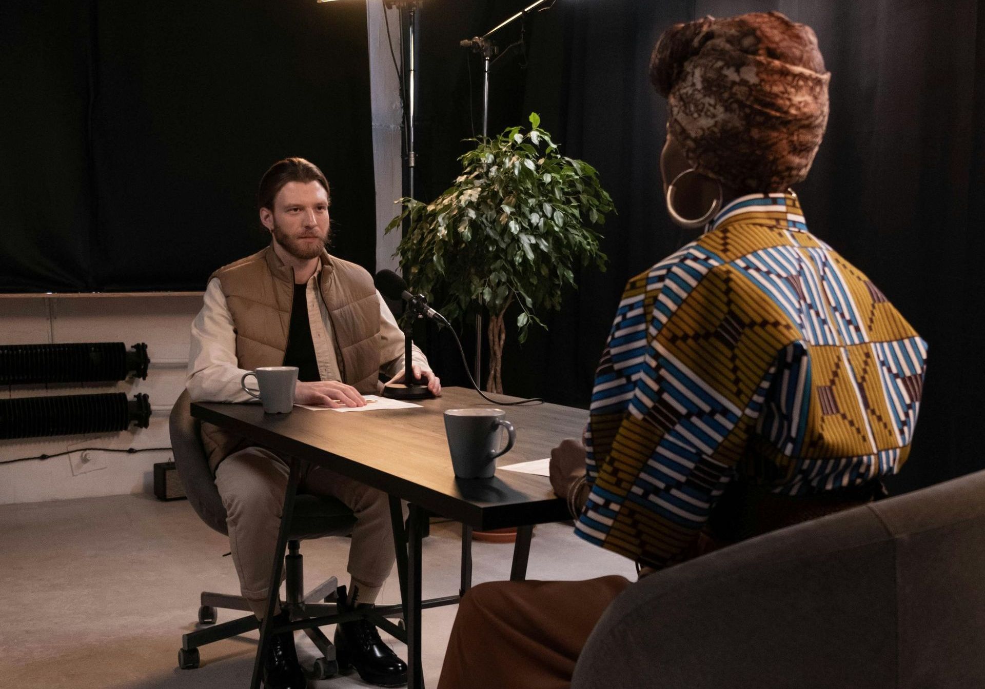 A man and a woman are sitting at a table talking to each other.