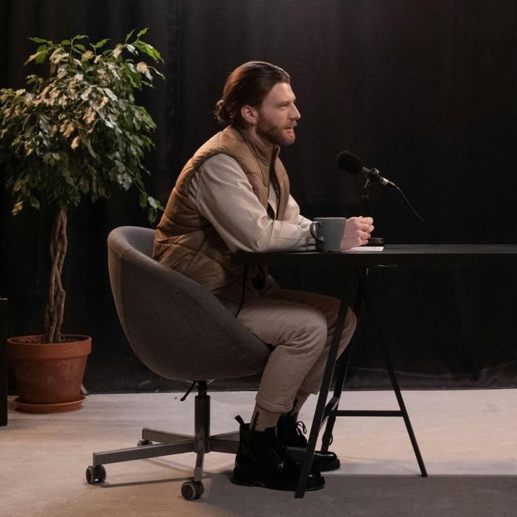 A man is sitting at a desk with a microphone in front of him