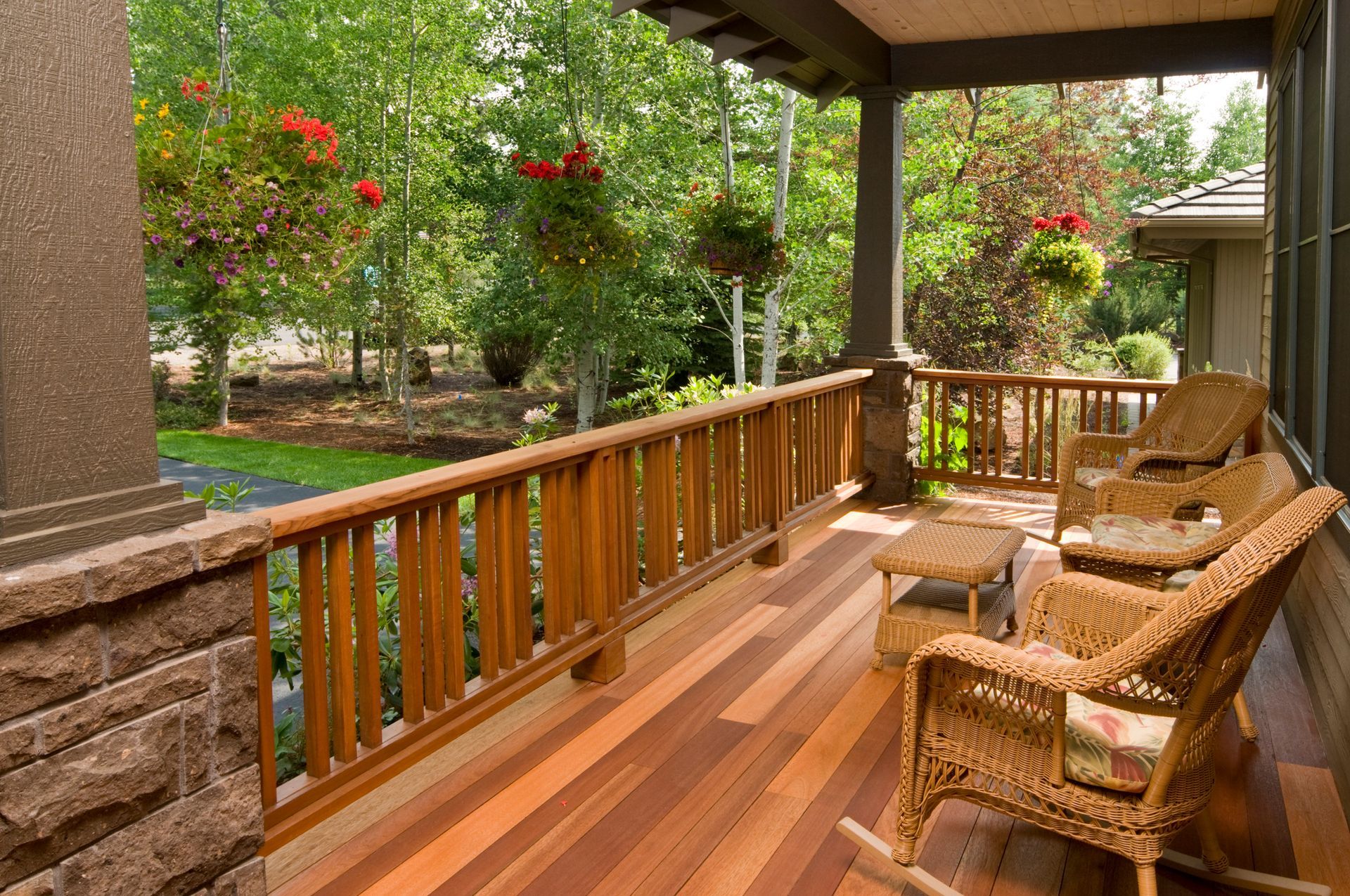 A wooden porch with rocking chairs and a table