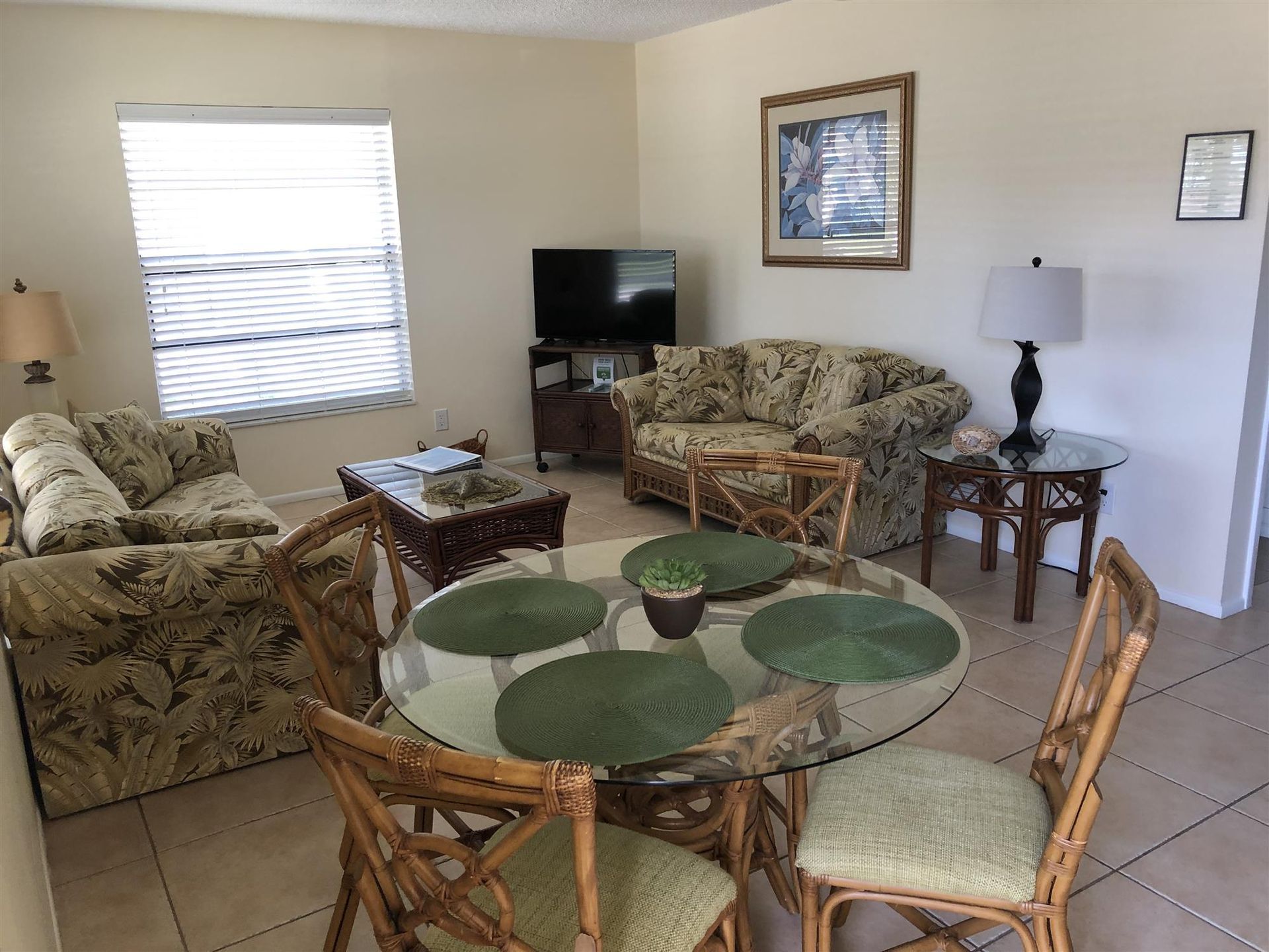 A living room with a couch , chairs , a table and a television.
