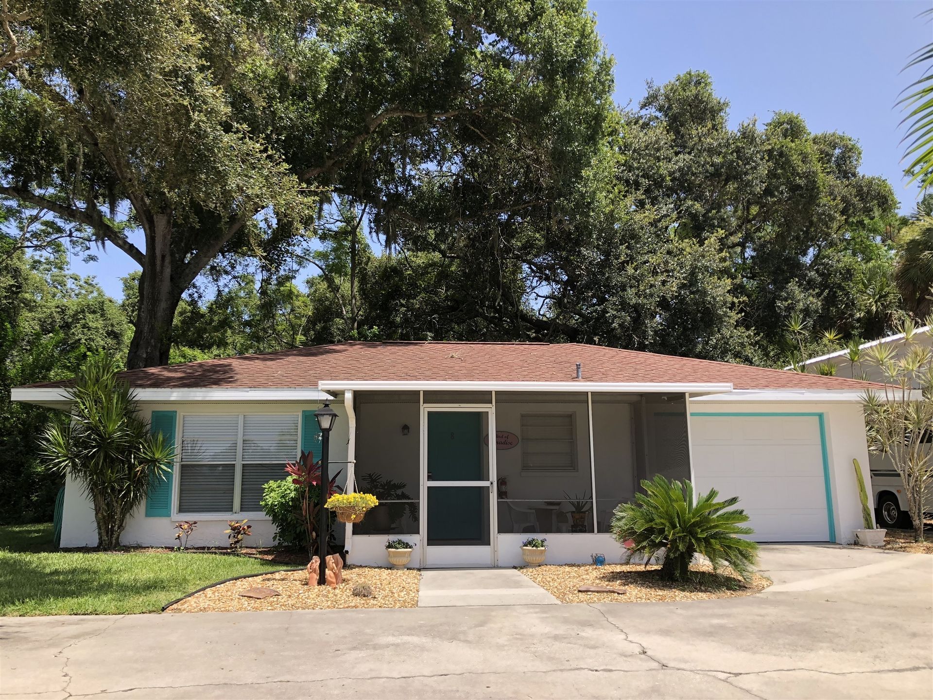 A white house with a screened in porch and a red roof