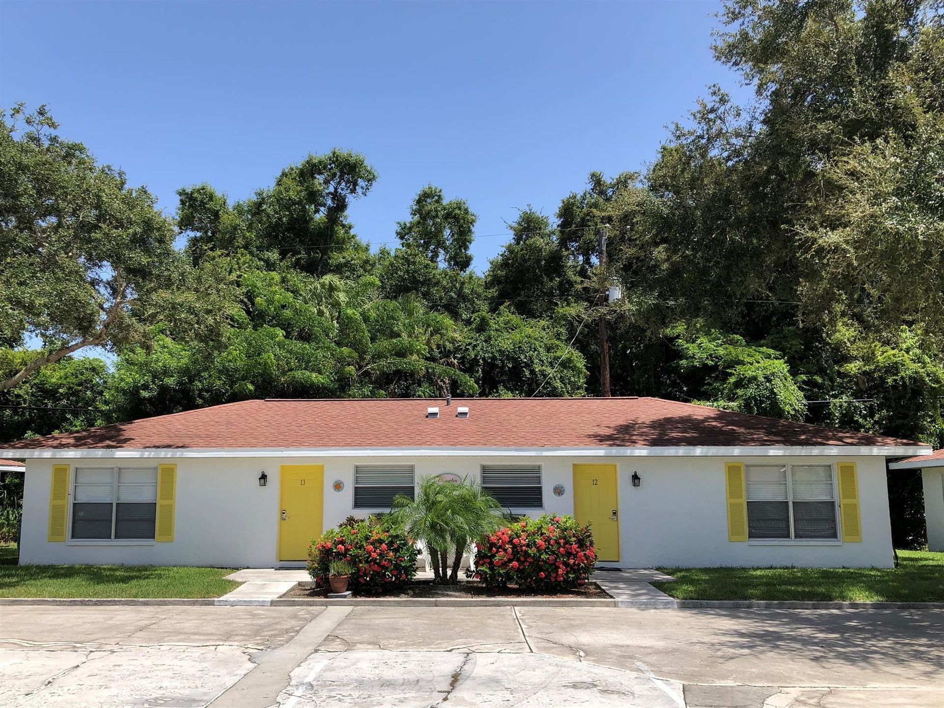 A white house with a red roof and yellow shutters