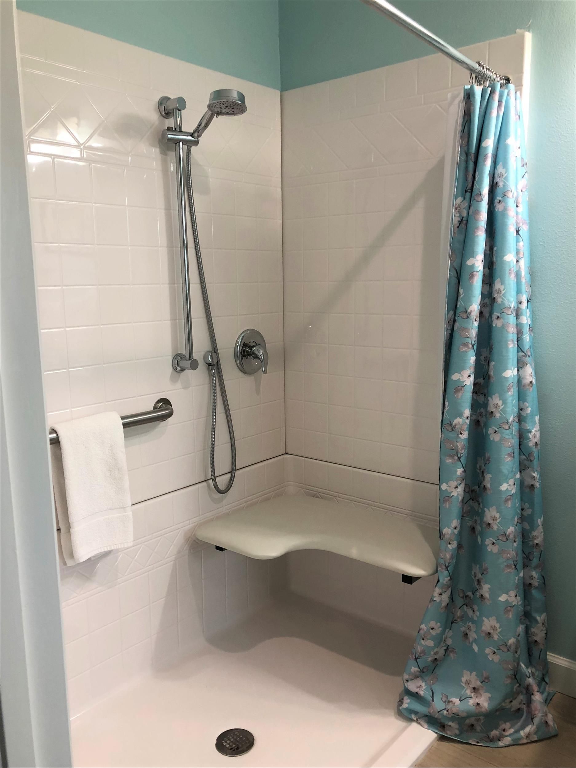 A bathroom with a shower and a blue shower curtain.