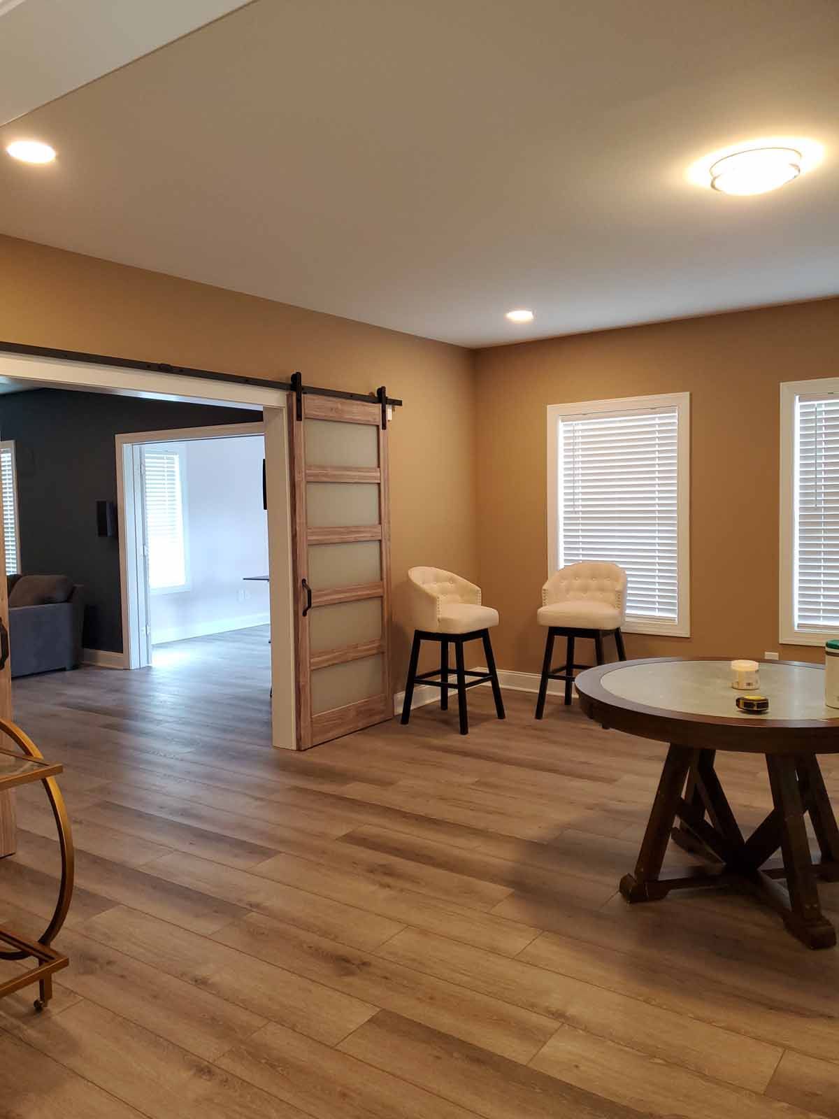A living room with a table and chairs and a sliding barn door.