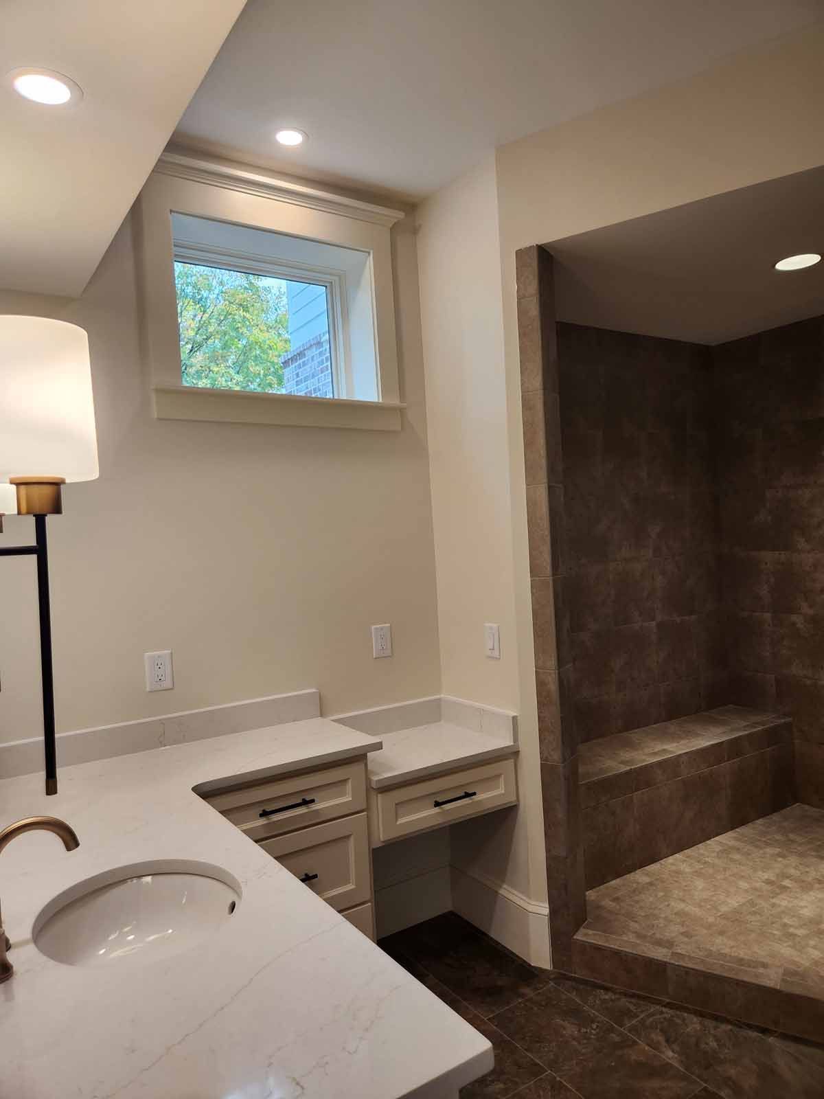 A bathroom with two sinks , a window and a walk in shower.