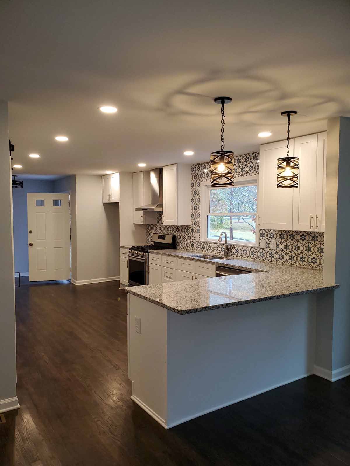 A kitchen with white cabinets , granite counter tops , and stainless steel appliances.