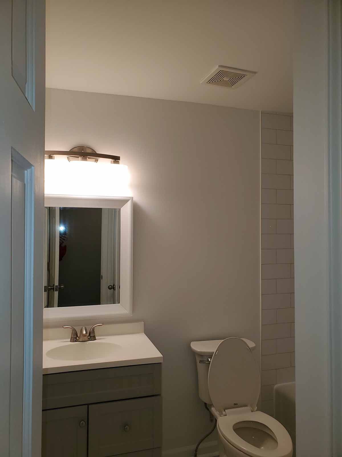 A bathroom with a toilet , sink and mirror.