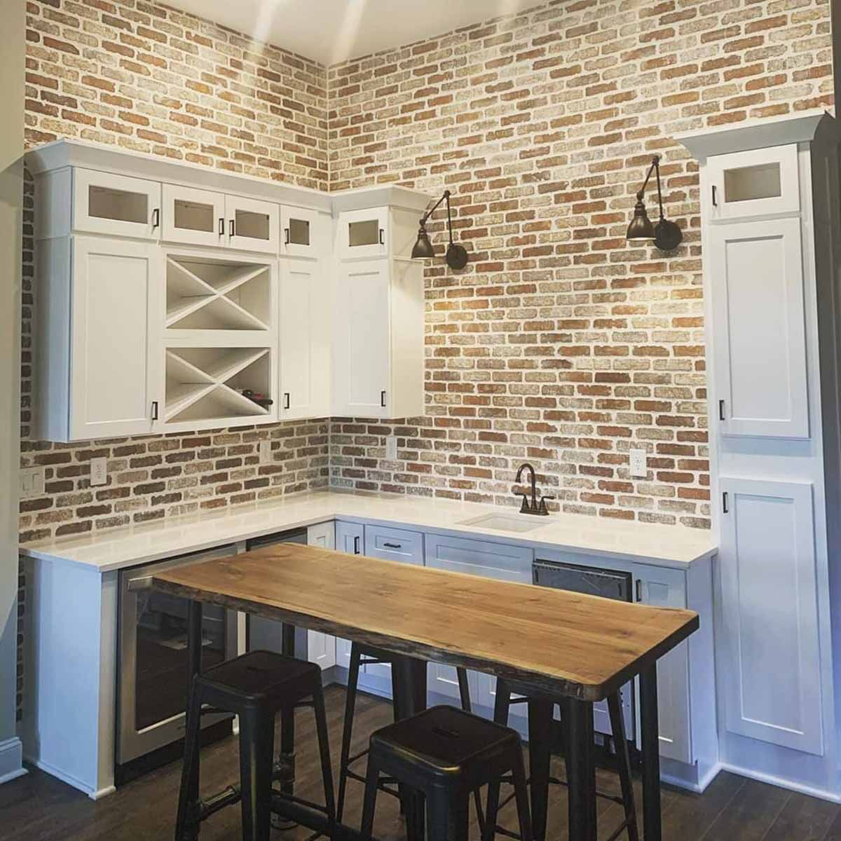 A kitchen with a wooden table and stools and a brick wall.