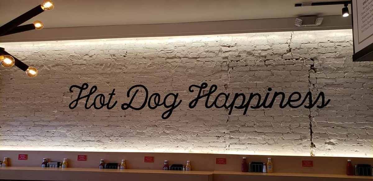 A brick wall with the words `` hot dog happiness '' written on it.