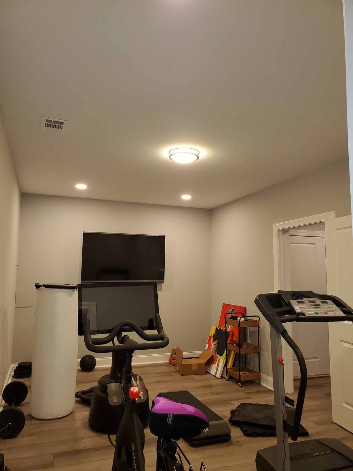 A home gym with a bicycle , treadmill , and television.