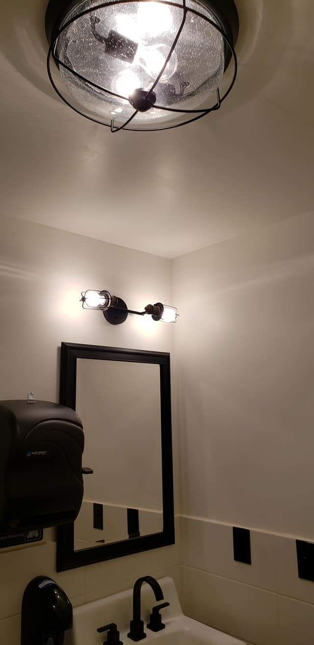 A bathroom with a sink , mirror and light fixture.
