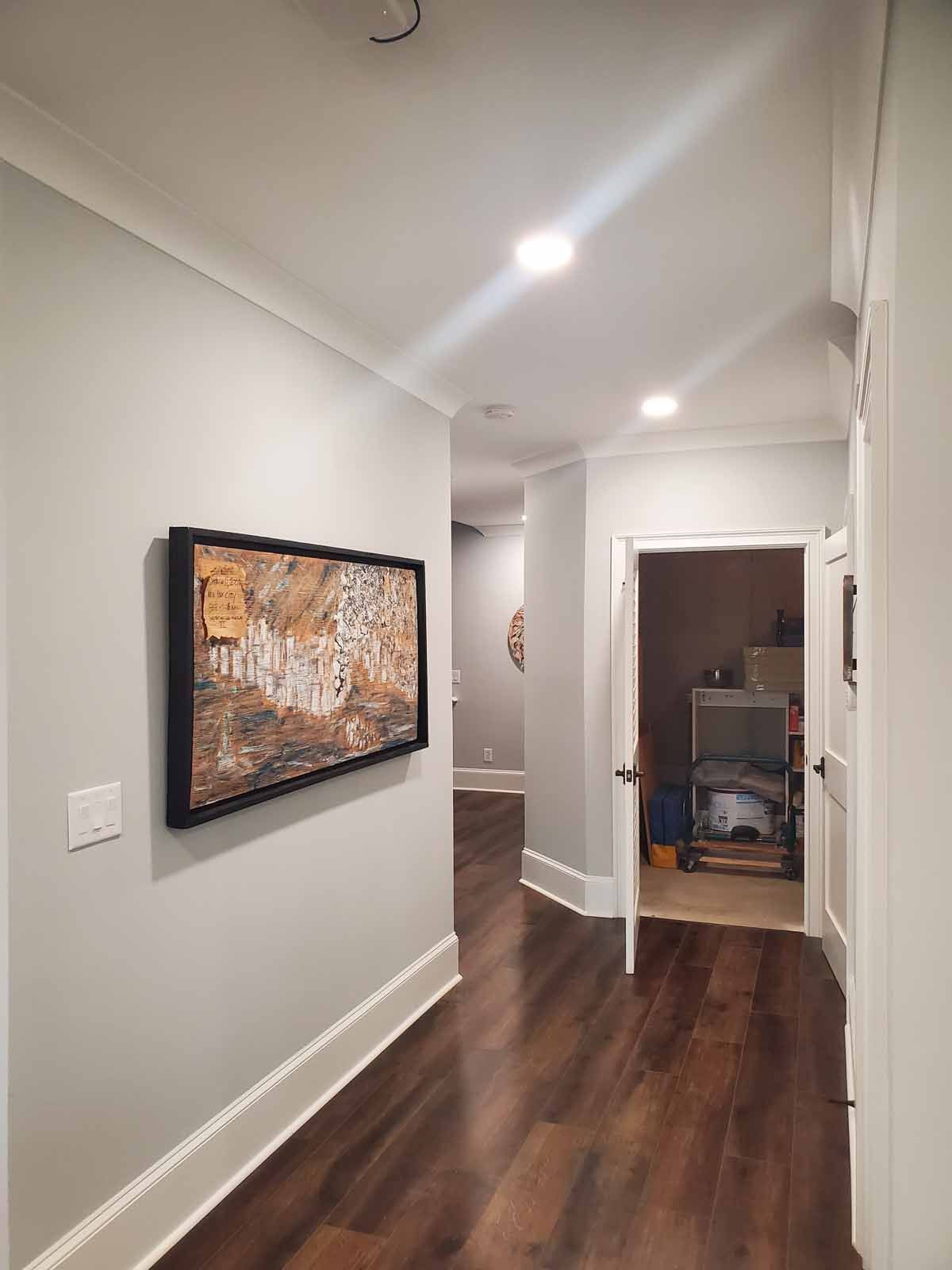 A hallway with hardwood floors and a painting on the wall.