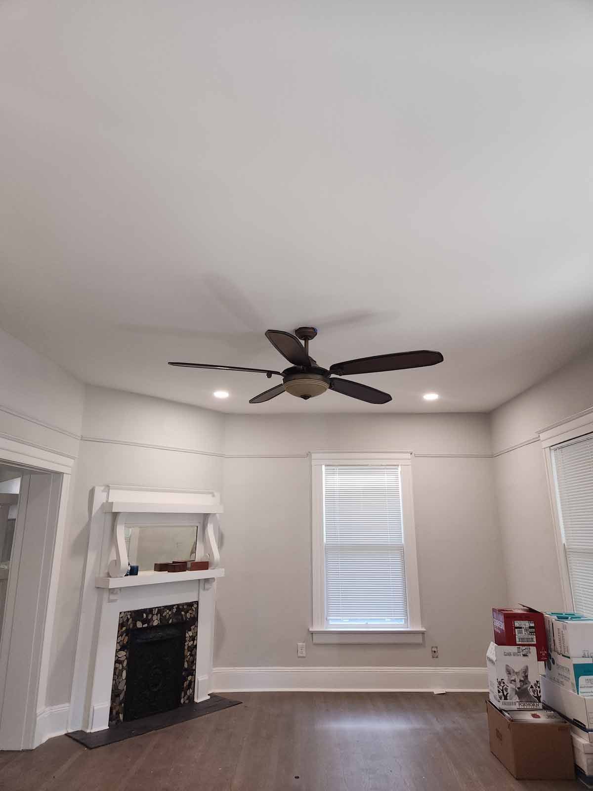 A living room with a fireplace and a ceiling fan.