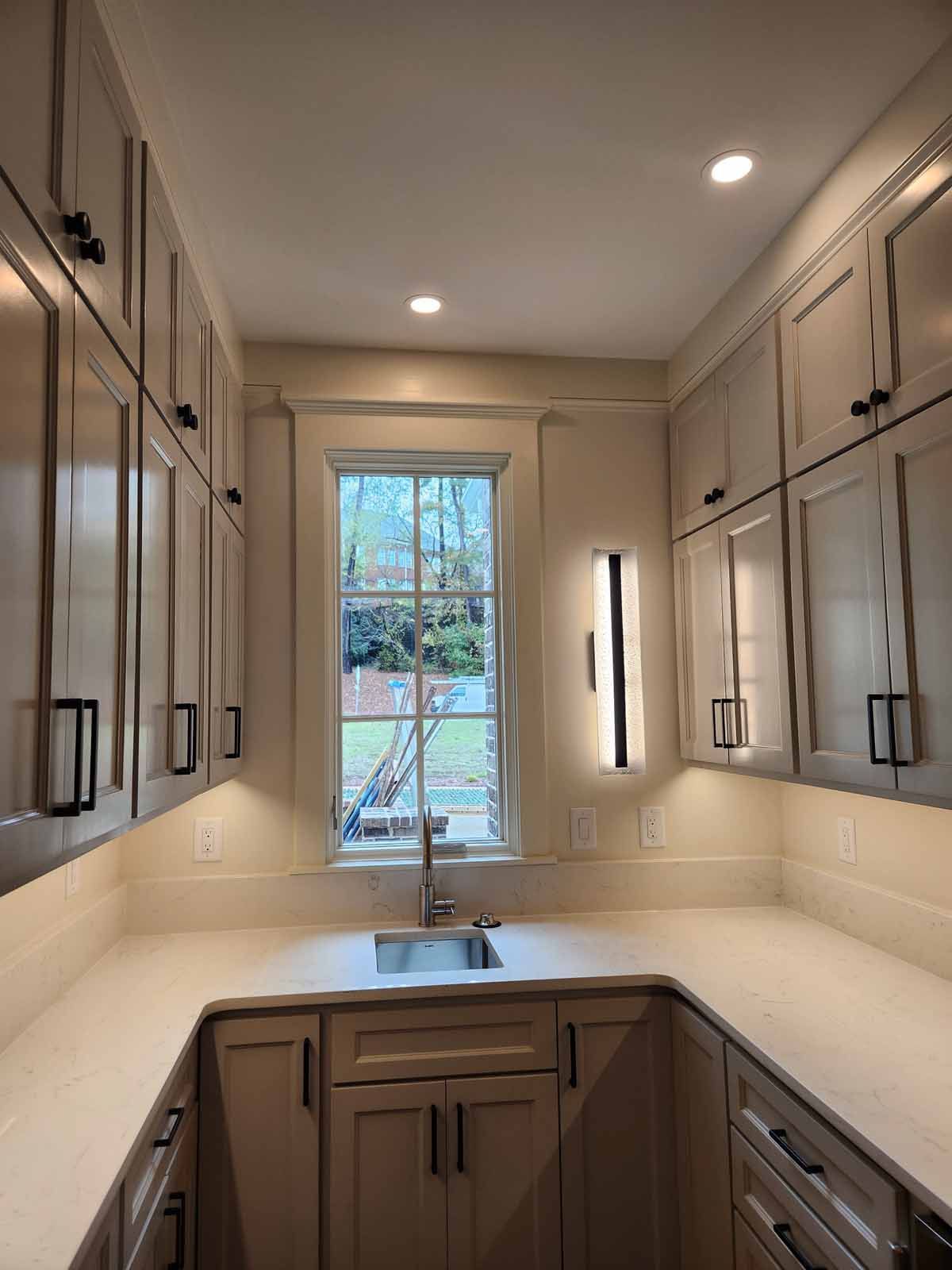 A kitchen with a sink , cabinets , and a window.