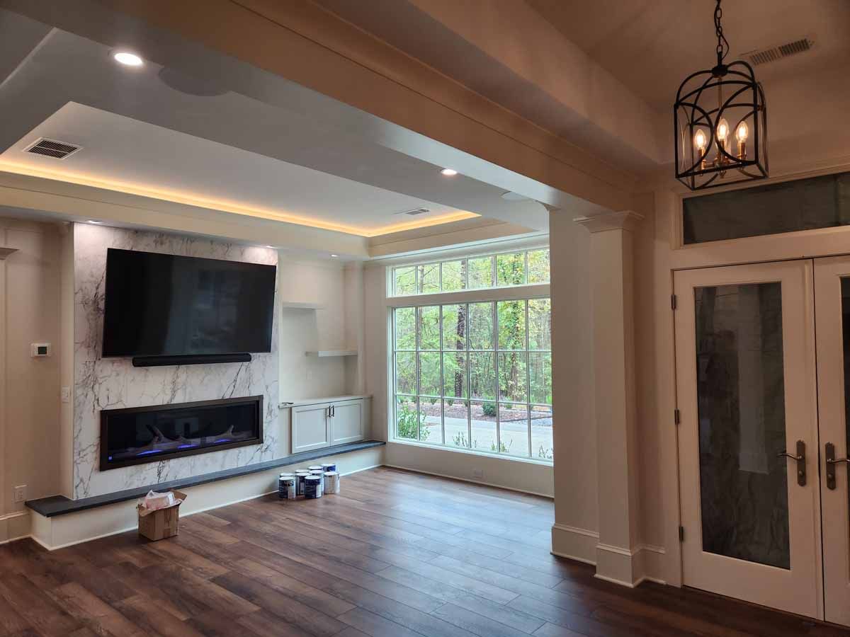 A living room with a fireplace , television , and large windows.
